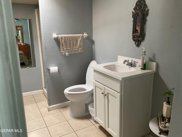 bathroom featuring toilet, tile patterned flooring, baseboards, and vanity