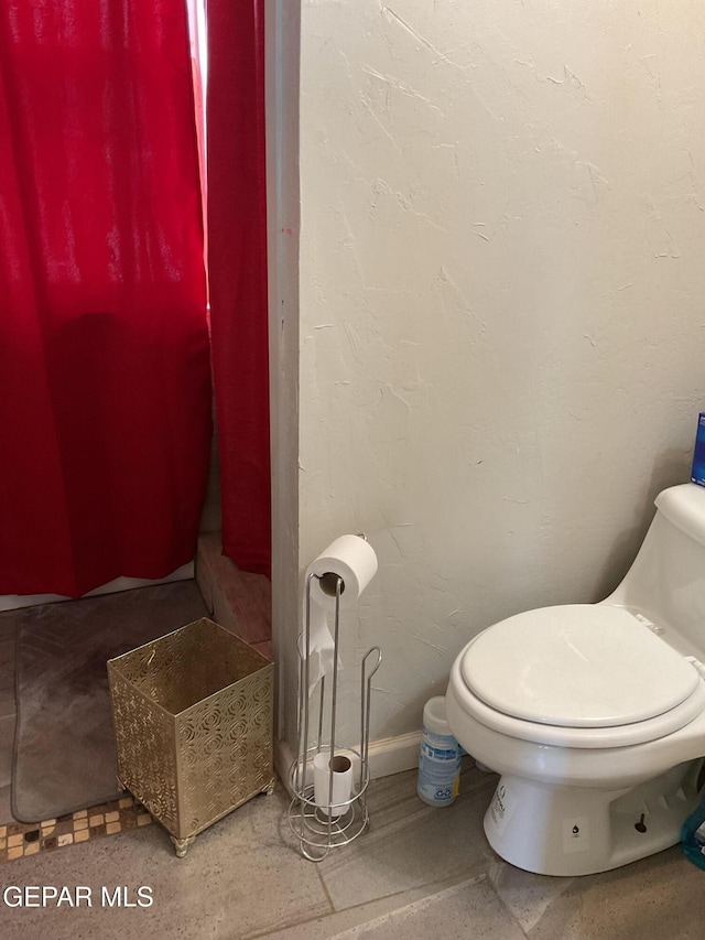 bathroom featuring baseboards and toilet