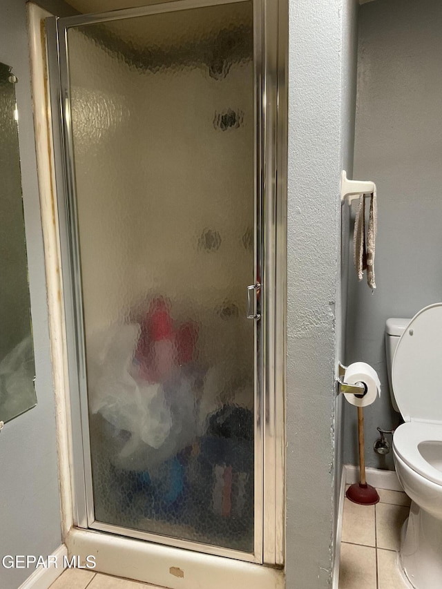 full bathroom with a stall shower, toilet, and tile patterned floors