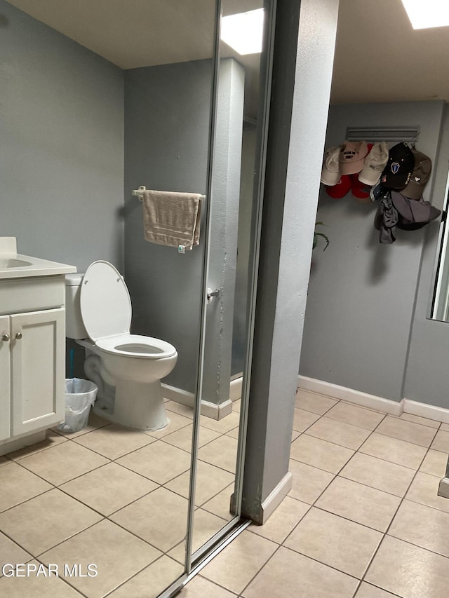 bathroom featuring baseboards, vanity, toilet, and tile patterned floors