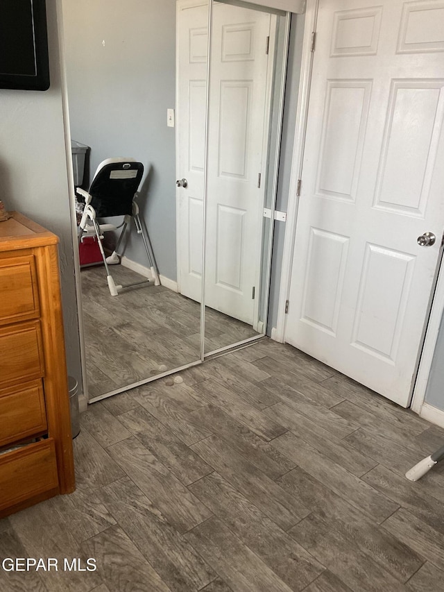 bedroom featuring dark wood-style flooring, a closet, and baseboards