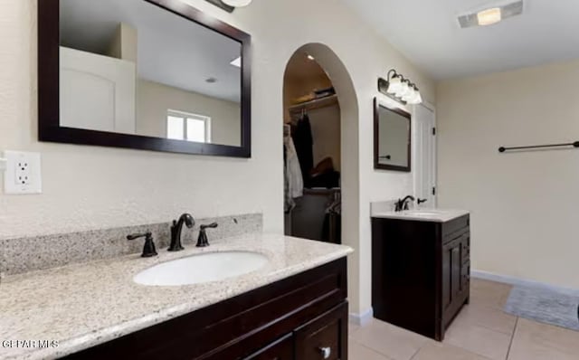 bathroom with two vanities, a sink, baseboards, and tile patterned floors