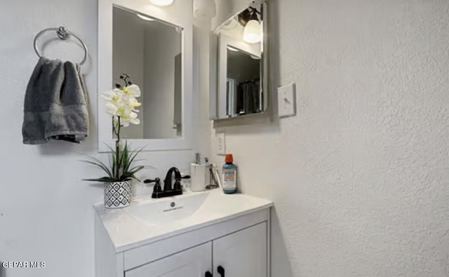 bathroom with a textured wall and vanity