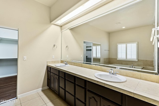 full bath featuring double vanity, tile patterned flooring, a sink, and a bath