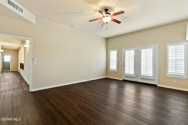 interior space featuring a wealth of natural light, a ceiling fan, visible vents, and dark wood-style flooring