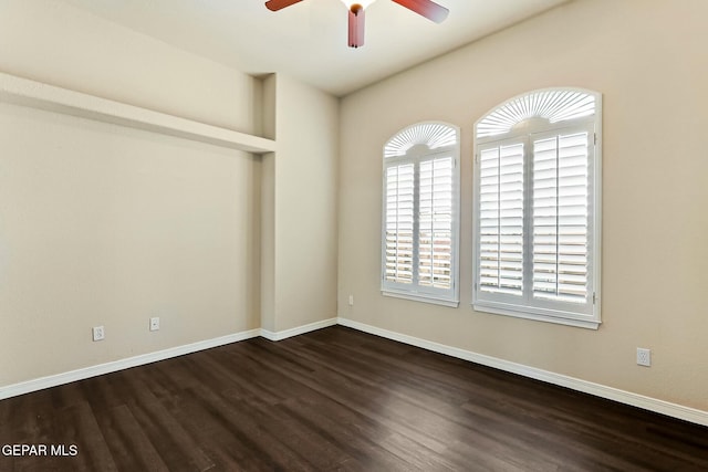 spare room with a ceiling fan, baseboards, and dark wood-style flooring