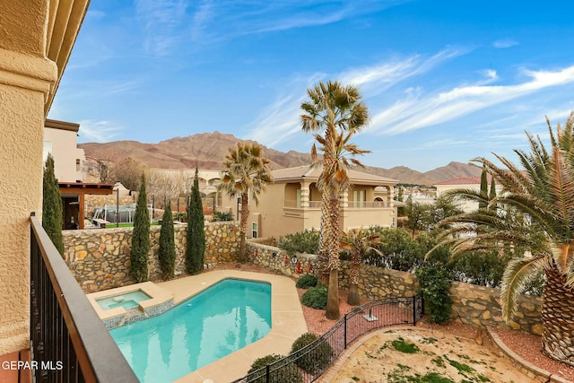 view of swimming pool with a pool with connected hot tub, a mountain view, and fence