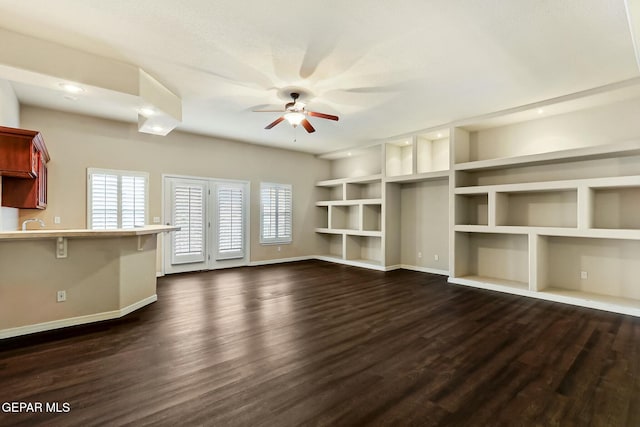 unfurnished living room featuring ceiling fan, baseboards, and dark wood-style flooring