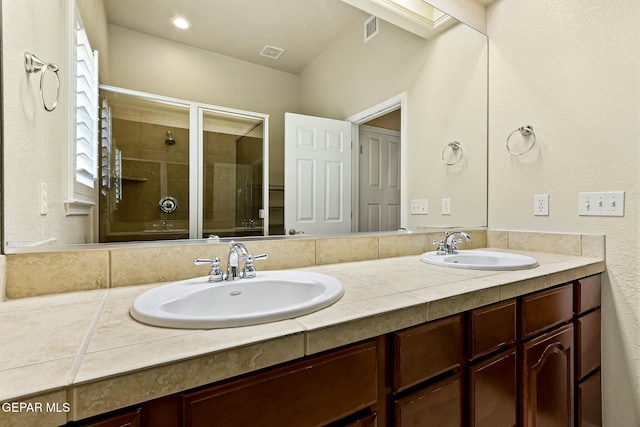 bathroom featuring double vanity, a shower stall, visible vents, and a sink