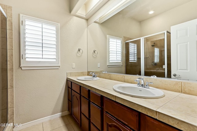 bathroom featuring double vanity, a stall shower, a sink, and tile patterned floors