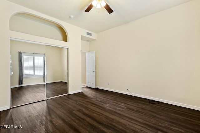 unfurnished bedroom with visible vents, baseboards, a ceiling fan, dark wood finished floors, and a closet