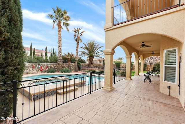 view of patio with a fenced in pool, fence, a balcony, and a ceiling fan