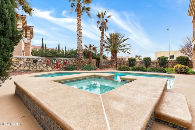 view of swimming pool featuring a pool with connected hot tub and fence