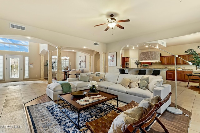 living area featuring arched walkways, a healthy amount of sunlight, visible vents, and light tile patterned flooring