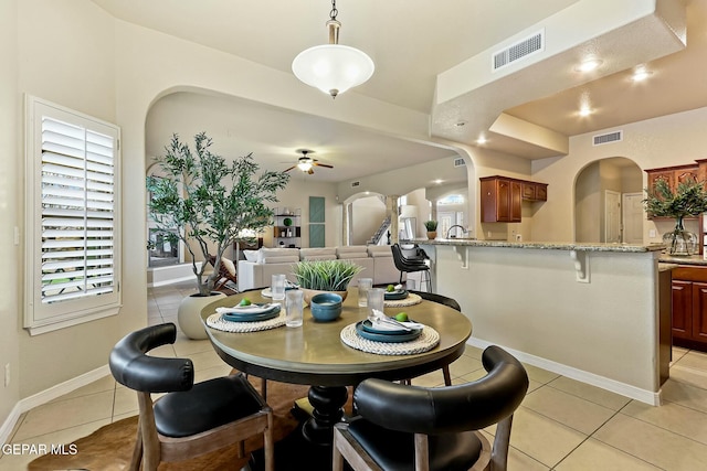 dining area with arched walkways, visible vents, light tile patterned flooring, and a ceiling fan