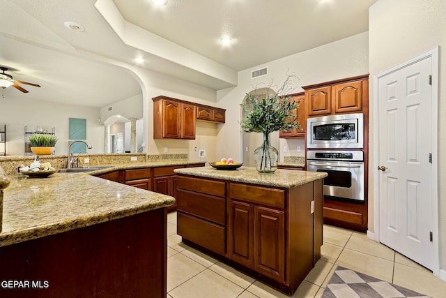 kitchen with light tile patterned floors, arched walkways, stainless steel appliances, a sink, and visible vents