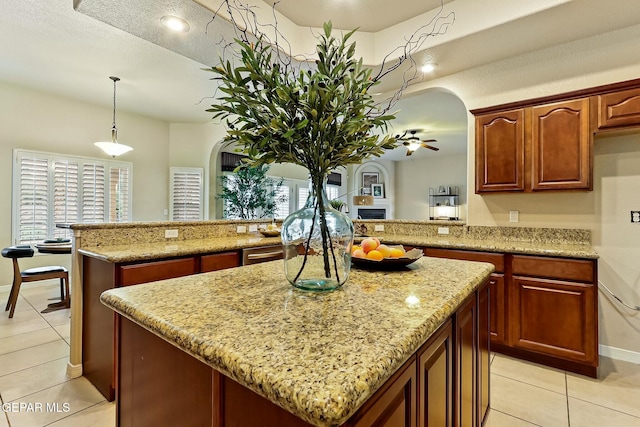 kitchen with arched walkways, hanging light fixtures, a peninsula, and a kitchen island