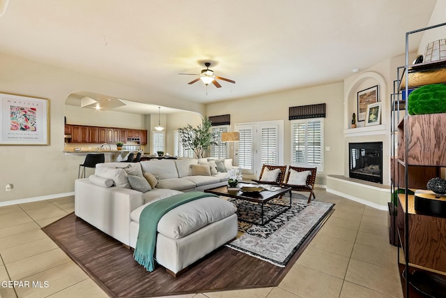 living area with a ceiling fan, light tile patterned flooring, a fireplace, and baseboards