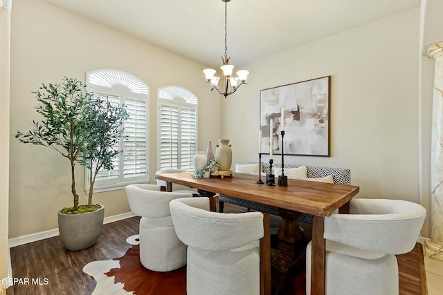 dining area with dark wood-style floors, a chandelier, and baseboards