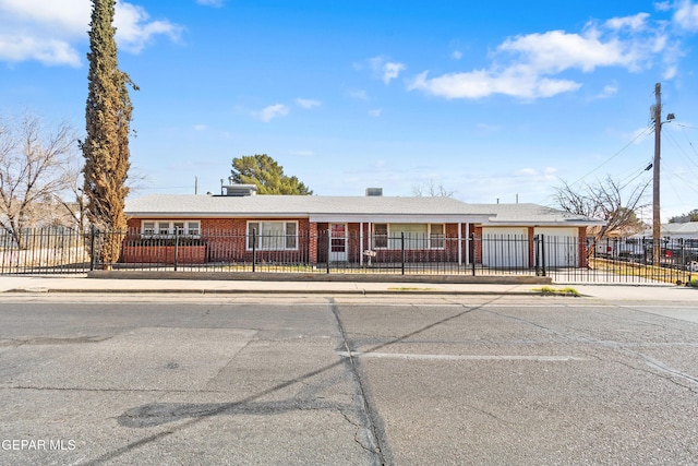 single story home with a garage, a fenced front yard, concrete driveway, and brick siding