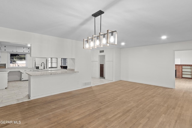 unfurnished living room with light wood finished floors, a sink, and visible vents