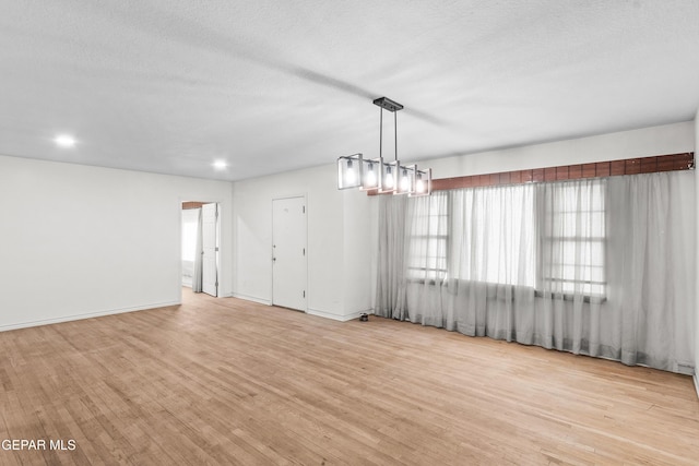 interior space featuring a textured ceiling, light wood finished floors, and baseboards