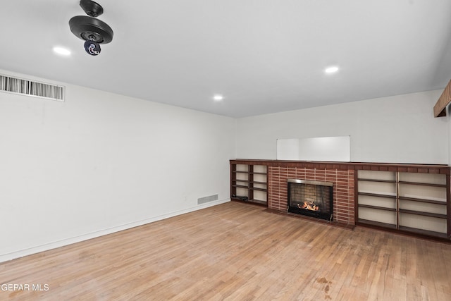 unfurnished living room featuring light wood-type flooring, baseboards, a fireplace, and visible vents