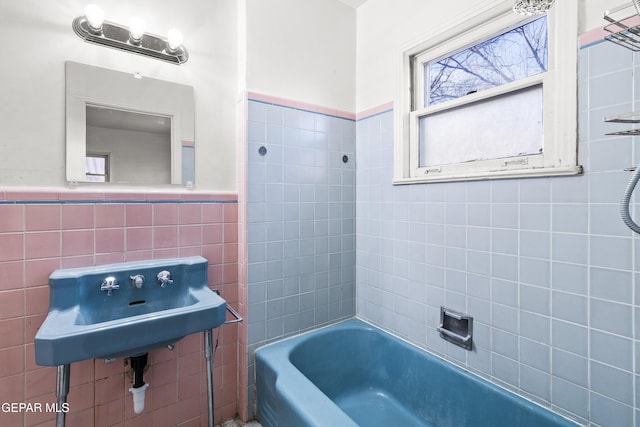 full bathroom featuring wainscoting, a sink, and tile walls