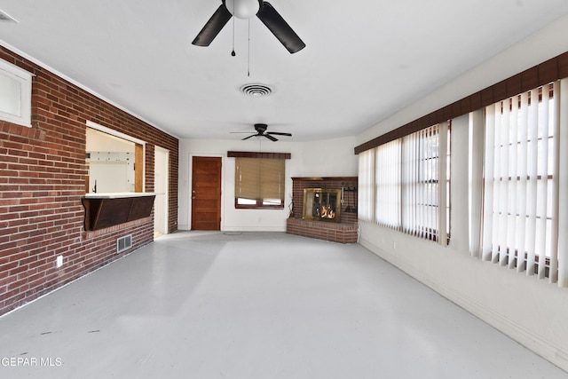 unfurnished living room featuring brick wall, concrete floors, a fireplace, and visible vents