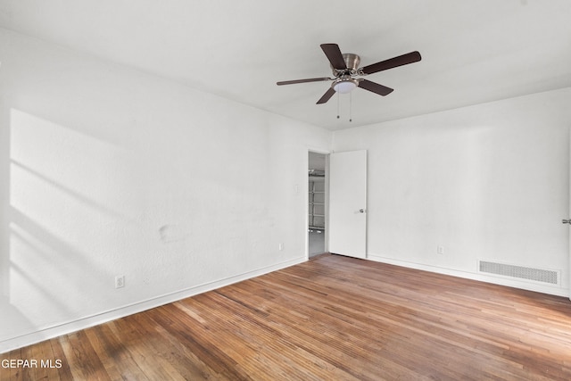 empty room featuring visible vents, ceiling fan, baseboards, and wood finished floors