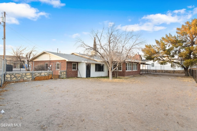 rear view of property with driveway, brick siding, and a fenced front yard