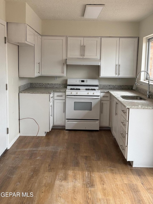 kitchen featuring white range with gas stovetop, dark wood-style flooring, a sink, under cabinet range hood, and a textured ceiling