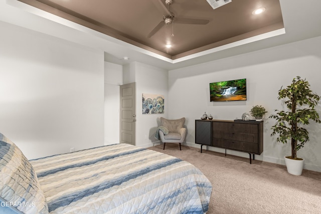 carpeted bedroom with a tray ceiling, recessed lighting, and baseboards