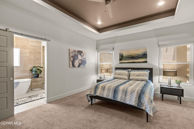 bedroom featuring carpet floors, a barn door, and a raised ceiling