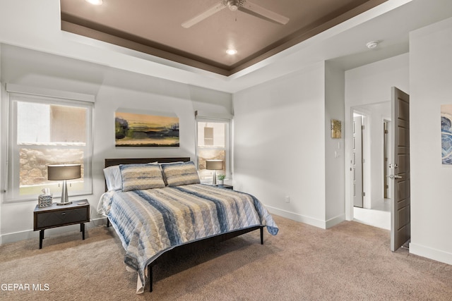 bedroom with baseboards, a tray ceiling, and light colored carpet