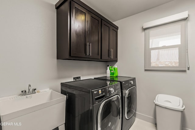 washroom featuring washing machine and clothes dryer, a sink, cabinet space, and baseboards