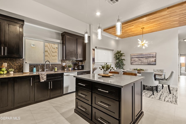 kitchen featuring a sink, a kitchen island, stainless steel dishwasher, backsplash, and decorative light fixtures