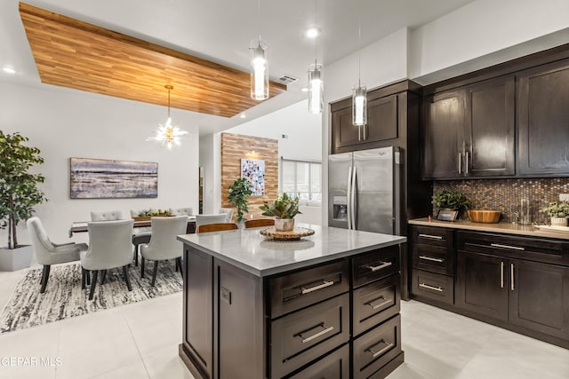 kitchen featuring a kitchen island, stainless steel fridge with ice dispenser, dark brown cabinets, decorative backsplash, and pendant lighting