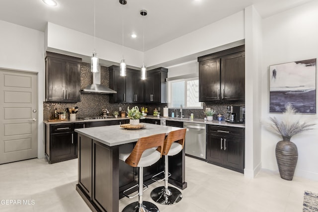 kitchen featuring a center island, decorative light fixtures, stainless steel appliances, light countertops, and wall chimney range hood