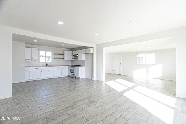 unfurnished living room with recessed lighting, baseboards, a sink, and wood finish floors