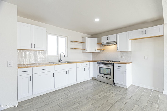 kitchen with open shelves, white cabinets, a sink, stainless steel gas range, and under cabinet range hood