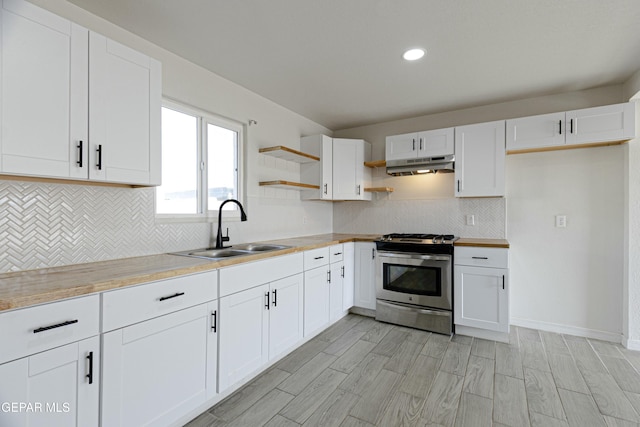 kitchen featuring stainless steel range with gas cooktop, light countertops, white cabinets, a sink, and under cabinet range hood