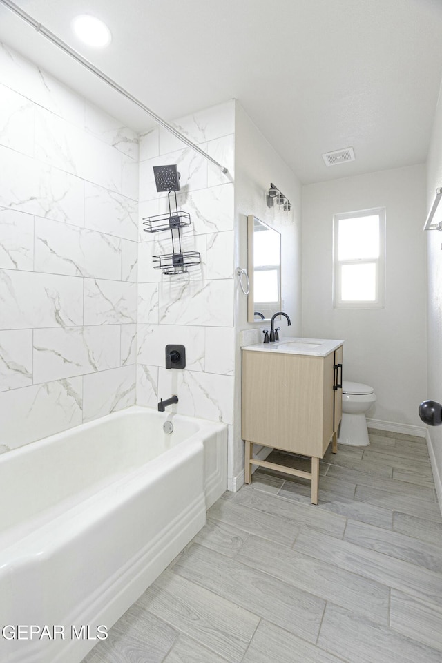 bathroom featuring visible vents, toilet, vanity,  shower combination, and baseboards