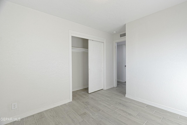 unfurnished bedroom featuring baseboards, visible vents, a closet, and wood finish floors