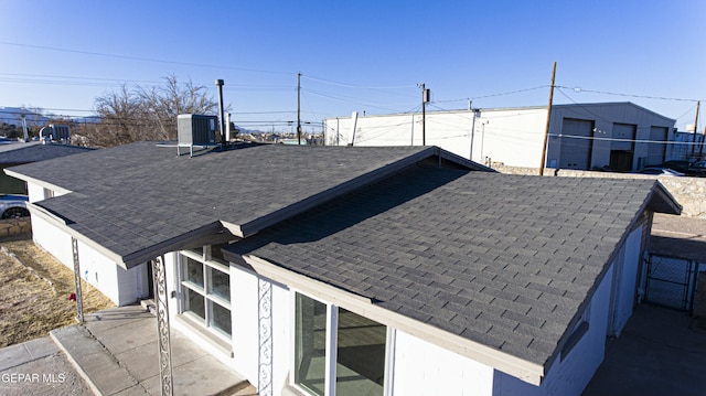 view of property exterior featuring central AC, a shingled roof, and fence