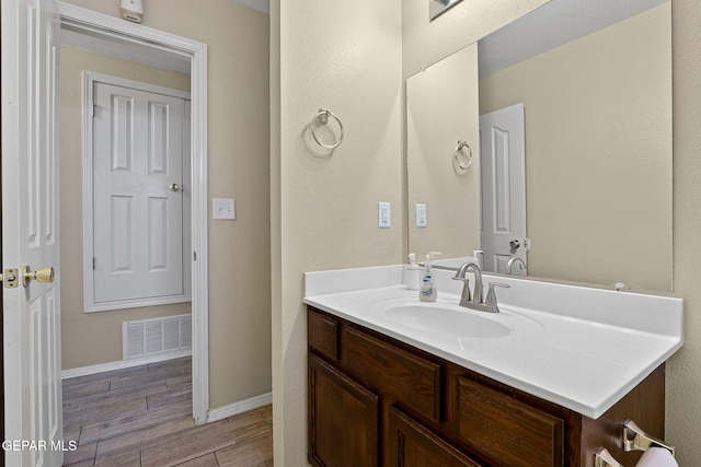 bathroom with wood finish floors, visible vents, vanity, and baseboards