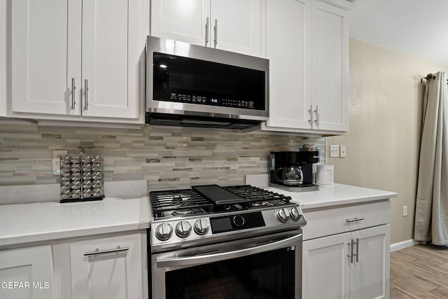 kitchen featuring decorative backsplash, white cabinetry, stainless steel appliances, and light countertops