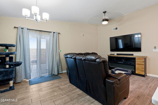 living room with wood tiled floor, visible vents, baseboards, and ceiling fan with notable chandelier