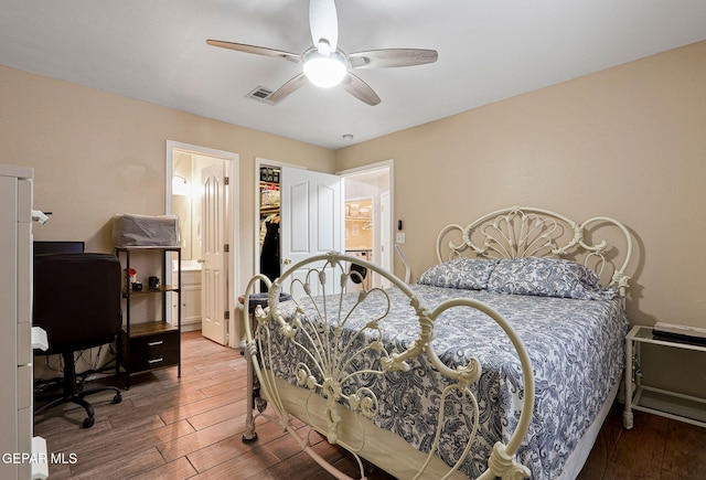 bedroom featuring a ceiling fan, visible vents, connected bathroom, and wood finished floors