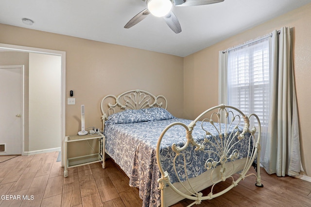 bedroom with ceiling fan, wood finished floors, and baseboards